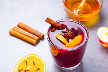 Çimento arka planında baharat olan bir bardak sıcak şarap. Noel şarabı, portakal, elma, yıldız anason ve tarçınlı. Kırmızı şarap ve bal gri arka planda. Üst Manzara. Boşluğu kopyala