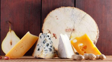Tahta tahtalarda çeşitli peynir, armut ve fıstık çeşitleri. Camembert peyniri, sert sarı peynir, ahşap arka planda Dorblu. Süt ürünleri, armut ve fındık. Geniş Ekran