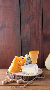 Tahta tahtalarda çeşitli peynir, armut ve fıstık çeşitleri. Camembert peyniri, sert sarı peynir, ahşap arka planda Dorblu. Süt ürünleri, armut ve fındık. Geniş Ekran