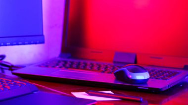 Neon ışığı altında serbest çalışan bir işyeri. Bilgisayar, grafiksel tablet ve akıllı telefon masaya. Mavi pembe ışıkta yaratıcılık için bir yer. Geniş Ekran