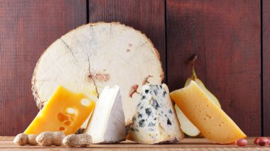 Tahta tahtalarda çeşitli peynir, armut ve fıstık çeşitleri. Camembert peyniri, sert sarı peynir, ahşap arka planda Dorblu. Süt ürünleri, armut ve fındık. Geniş Ekran