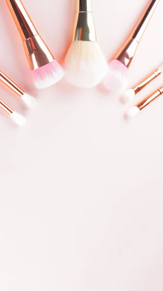 Makeup brushes on pink background. Set of golden makeup brushes, concept. Woman beauty accessory in pastel colors. Copy space. Widescreen