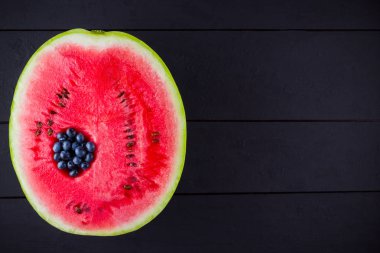 Karpuz ve koyu arka planda yaban mersini. Karpuzda yaban mersini. Yaratıcı gıda konsepti. Üstte görüntü