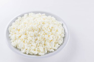 Beyaz tabakta süzme peynir. Beyaz arka planda taze süzme peynir. Minimalizm tarzında ev yapımı kaymak. Üst Manzara. Boşluğu kopyala