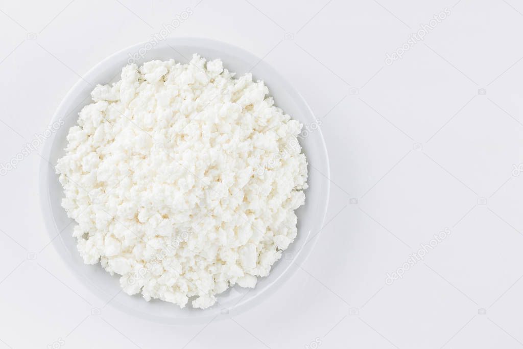 Cottage cheese in a white plate. Fresh cottage cheese on a white background. Homemade curd in minimalism style. Top view. Copy space