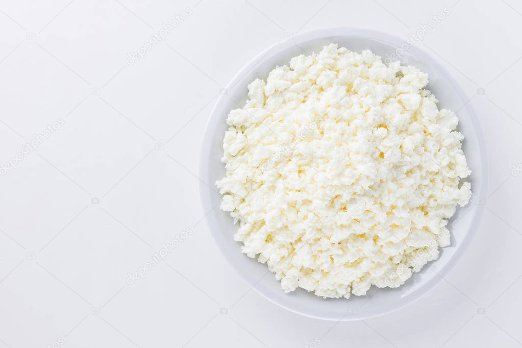 Cottage cheese in a white plate. Fresh cottage cheese on a white background. Homemade curd in minimalism style. Top view. Copy space