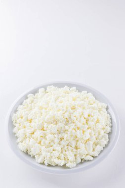 Cottage cheese in a white plate. Fresh cottage cheese on a white background. Homemade curd in minimalist style. Top view. Copy space