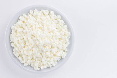 Cottage cheese in a white plate. Fresh cottage cheese on a white background. Homemade curd in minimalist style. Top view. Copy space