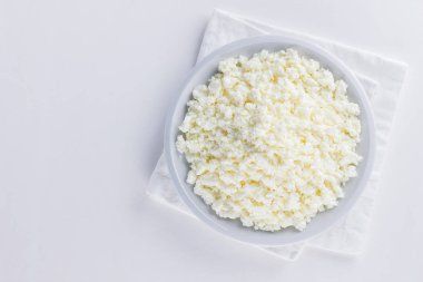 Cottage cheese in a white plate. Fresh cottage cheese on a white background. Homemade curd in minimalist style. Top view. Copy space