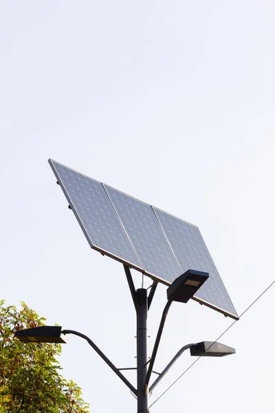 Solar device with street lamp on background of blue sky. Street light powered by solar panel with battery included. Alternative energy from the sun. Copy space