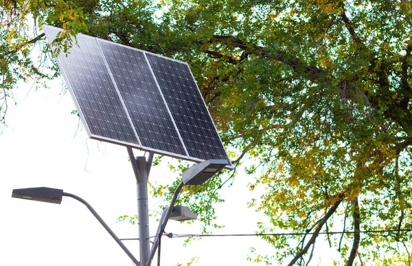 Solar device with street lamp on background of blue sky. Street light powered by solar panel with battery included. Alternative energy from the sun. Copy space