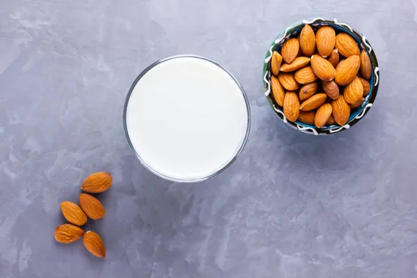 Almond milk with almond on gray background. Homemade organic almond milk in a glass for healthy breakfast. Vegan milk from almonds nuts on a cement. Alternative milk. Top view. Copy space
