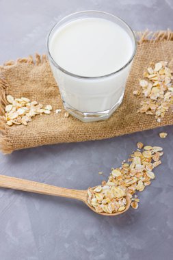 Yulaf sütü. Organik yulaf sütü ve çuval bezi. Sağlıklı vejetaryen sütsüz organik içecek ve yulaf lapası. Beton arka planda sağlıklı bir süt. Sıfır kayıp. Boşluğu kopyala