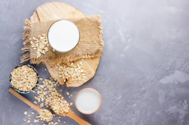 Yulaf sütü. Tahta tezgahta organik yulaf sütü. Sütsüz vejetaryen organik içecek ve yulaf lapası. Alternatif süt çimento arka planda. Sıfır atık