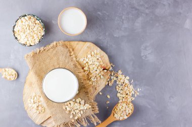 Yulaf sütü. Tahta tezgahta organik yulaf sütü. Sütsüz vejetaryen organik içecek ve yulaf lapası. Alternatif süt çimento arka planda. Sıfır atık