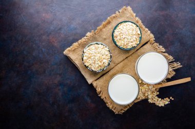 Yulaf sütü. Siyah arka planda organik yulaf sütü. Vegan sütsüz alternatif süt. Sağlıklı vejetaryen sütü. Üst Manzara. Düz yatıyordu