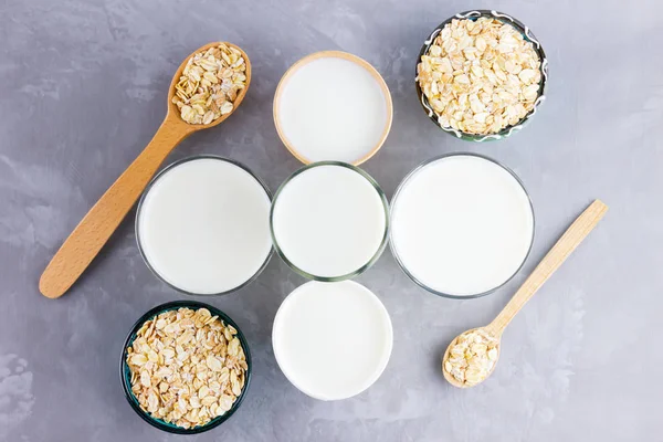 Concept of oat milk. Organic oat milk on a wooden stand. Vegan non dairy alternative milk. Healthy vegan milk on cement background. Zero waste. Top view. Flat lay