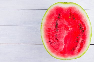 Beyaz arka planda karpuzun yarısı. Tahta tahtalarda dilimlenmiş karpuz. Vegan için sağlıklı bir besin. Üstte görüntü