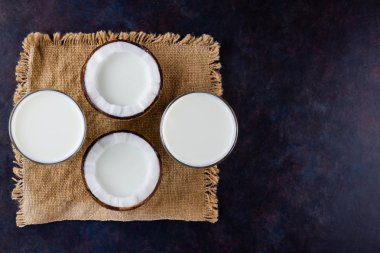 Hindistan cevizi sütü ve cam kaplı hindistan cevizi. Hindistancevizi vejetaryen sütü çuval bezinin üzerinde. Sağlıklı içki konsepti. Alternatif süt. Düz yatıyordu