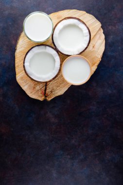 Hindistan cevizi sütü ve siyah arka planda kağıt bardakta hindistan cevizi. Tahta tezgahta hindistan cevizi vejetaryeni sütü var. Sağlıklı içki konsepti. Alternatif süt. Üst görünüm