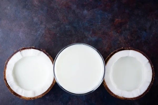 Coconut milk and coconut in glass on dark background. Coconut vegan milk non dairy with copy space. Healthy drink concept. Alternative milk. Flat lay