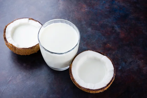 Coconut milk and coconut in glass on dark background. Coconut vegan milk non dairy with copy space. Healthy drink concept. Alternative milk. Flat lay