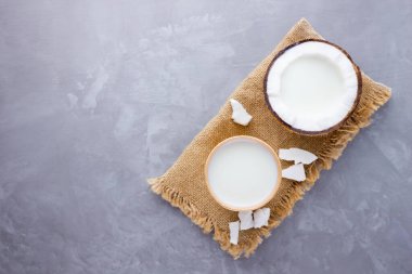 Hindistan cevizi sütü ve gri arka planda kağıt bardakta hindistan cevizi. Hindistancevizi vejetaryen sütü çuval bezinin üzerinde. Sağlıklı içki konsepti. Alternatif süt. Üst görünüm