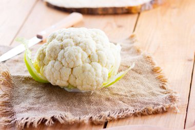 Ahşap arka planda organik karnabahar. Çuval bezinde karnabahar başı. Organik yiyecekler. Kırsal biçim