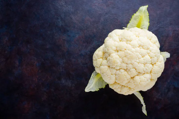 Cauliflower on dark background. Organic cauliflower on black background. Vegan healthy food. Minimalism