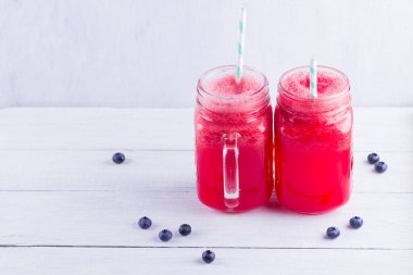 Karpuz dilimleri ile mason kavanozlarda karpuz içmek. Beyaz arka planda karpuz smoothies ve yaban mersini. Vejetaryen için yaz sağlıklı içecek. Kopyalama alanı