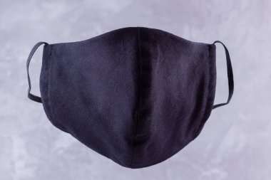 El yapımı koruyucu maske. Pamuktan yapılmış antivirüs maskesi. Salgın bir virüs olan COVID-19 sırasında siyah stil bir yüz maskesi. Gri arkaplanda yüz koruyucu maskesi