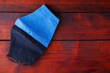 El yapımı koruyucu maskeler. Pamuktan yapılmış antivirüs maskeleri. Bir salgın virüsü COVID-19 sırasında mavi ve siyah maskeler. Tahtadaki koruyucu maskelerle yüzleş. Boşluğu kopyala