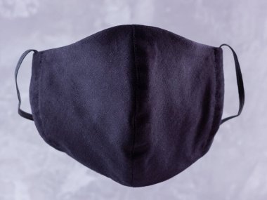 Koruyucu maske. Pamuktan yapılmış antivirüs maskesi. Salgın bir virüs olan COVID-19 sırasında siyah stil bir yüz maskesi. Gri arka planda yüz koruyucu maskesi
