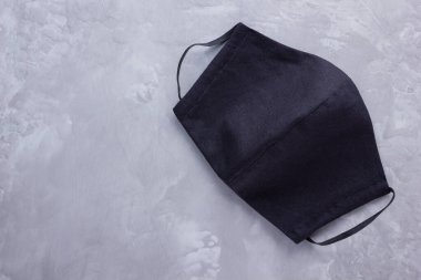 Yüz koruyucu maske. Siyah pamuktan yapılmış antivirüs maskesi. Salgın bir virüs olan COVID-19 sırasında siyah yüz maskesi. Gri arkaplanda koruyucu maske