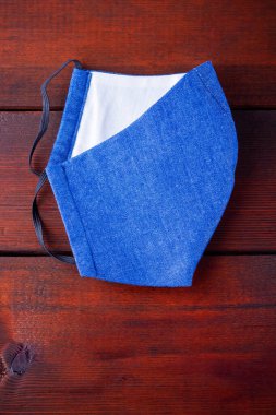 El yapımı koruyucu maske. Kot pantolondan yapılmış antivirüs maskesi. Mavi kot, COVID-19 salgını sırasında maske takıyordu. Tahta bir tahtanın üzerinde koruyucu maske. Boşluğu kopyala