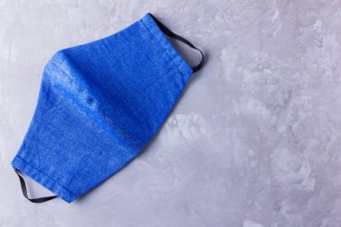 Yüz koruyucu maske. Kot pantolondan yapılmış antivirüs maskesi. Mavi beyaz kot, COVID-19 salgını sırasında maske takıyor. Gri arkaplanda koruyucu maske