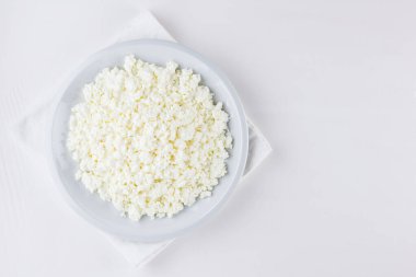 Beyaz arka planda bir tabakta süzme peynir. Beyaz peçetede süzme peynir. Üst Manzara. Boşluğu kopyala