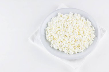 Beyaz arka planda bir tabakta süzme peynir. Beyaz peçetede süzme peynir. Üst Manzara. Boşluğu kopyala