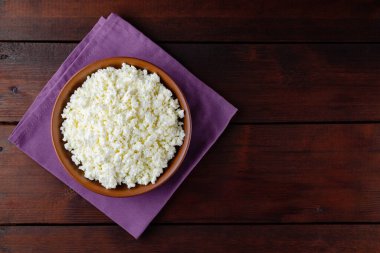 Ahşap tahtalardaki süzme peynir. Seramik kasede taze süzme peynir. Keten peçetede yumuşak peynirli kil tabağı. Üst Manzara. Boşluğu kopyala