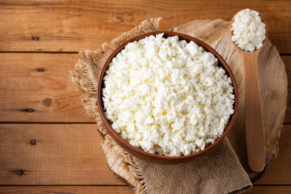 Ahşap tezgahta süzme peynir. Kâsede taze süzme peynir. Çuval bezinde yumuşak peynir ve tahta kaşık. Üst Manzara. Boşluğu kopyala