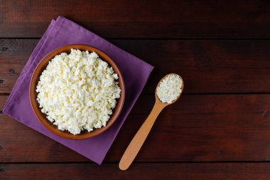 Ahşap tahtalardaki süzme peynir. Seramik kasede taze süzme peynir. Keten peçetede yumuşak peynirli kil tabağı. Üst Manzara. Boşluğu kopyala