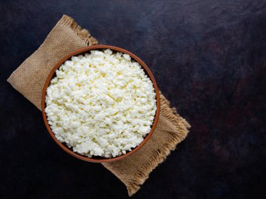 Çuval bezinde süzme peynir. Koyu bir arka planda taze süzme peynir. Siyah arka planda yumuşak peynir. Minimalizm. Üst Manzara. Boşluğu kopyala