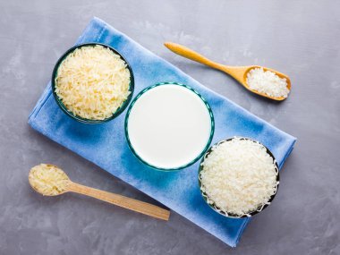 Gri arka planda pirinç ve süt tohumu. Mavi bir peçetede pirinç sütü. Çimento arka planında süt içermeyen vegan. Yükselişten gelen alternatif süt. Minimalizm. Boşluğu kopyala