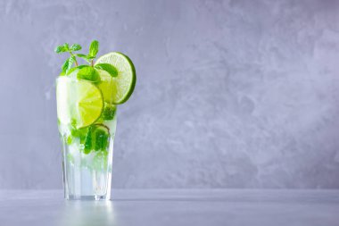 Limonlu mojito kokteyli ve uzun bardakta nane şekeri. Gri arka planda camlı taze mojito. Naneli kokteyli limonla tazeliyorum. Kaynamış su. Boşluğu kopyala