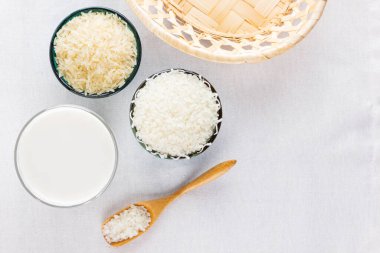 Beyaz arka planda pirinç sütü. Bardakta pirinç sütü ve pirinç tohumları. Keten kumaş üzerinde süt içermeyen vejetaryen süt. Yükselişten gelen alternatif süt. Minimalizm. Boşluğu kopyala