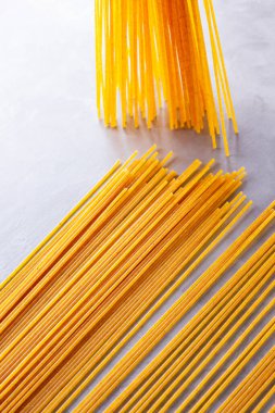 Gri arka planda sarı makarna. Çimento arka planında spagetti. Çiğ spagetti bolonez. Yemek geçmişi konsepti. Üst görünüm