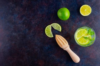 Limonlu kokteyl ve bardakta nane şekeri. Karanlık bir arka planda bir bardak mojito. Naneli kokteyli limonla tazeliyorum. Kaynamış su. Üst Manzara. Boşluğu kopyala