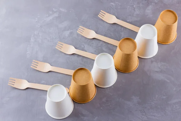 Zero waste. Disposable tableware. Eco-friendly disposable utensils made of bamboo wood and paper on a gray background. Paper cups, fast food containers and bamboo wooden cutlery