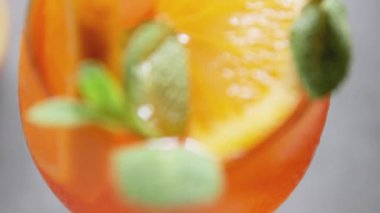 Gri arka planda Aperol Spritz kokteyli. Portakallı İtalyan alkolü kokteyli. Aperol Spritz ve taze nane ile dilimlenmiş portakal. Yakın plan.