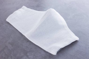 Beyaz tıbbi maske. Gri arka planda koruyucu gazlı bez maskesi. Pamuktan el yapımı antivirüs koruyucu maske. Gazlı bezden yapılmış koruyucu yüz maskesi. Minimalis